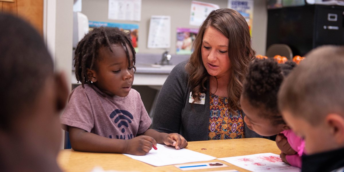 Dupaco helping student during a financial literacy lesson at Tri-County Head Start in Waterloo, Iowa.