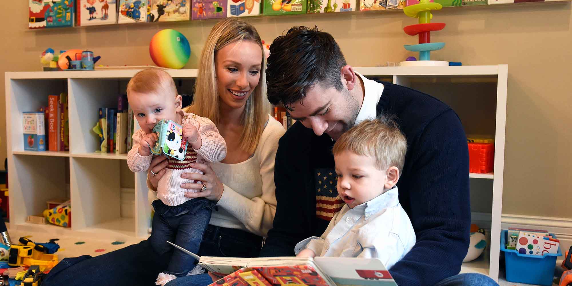 Dupaco credit union members happily posing with their two kids in their playroom, engaging in a joyful reading session.