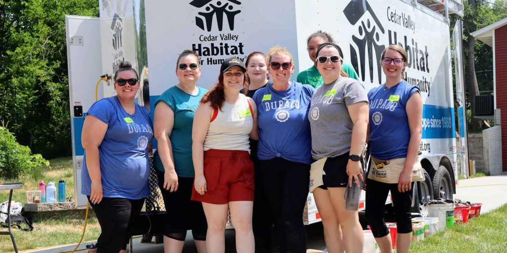 Dupaco employees stand in front of white Habitat for Humanity truck on a sunny summer day.