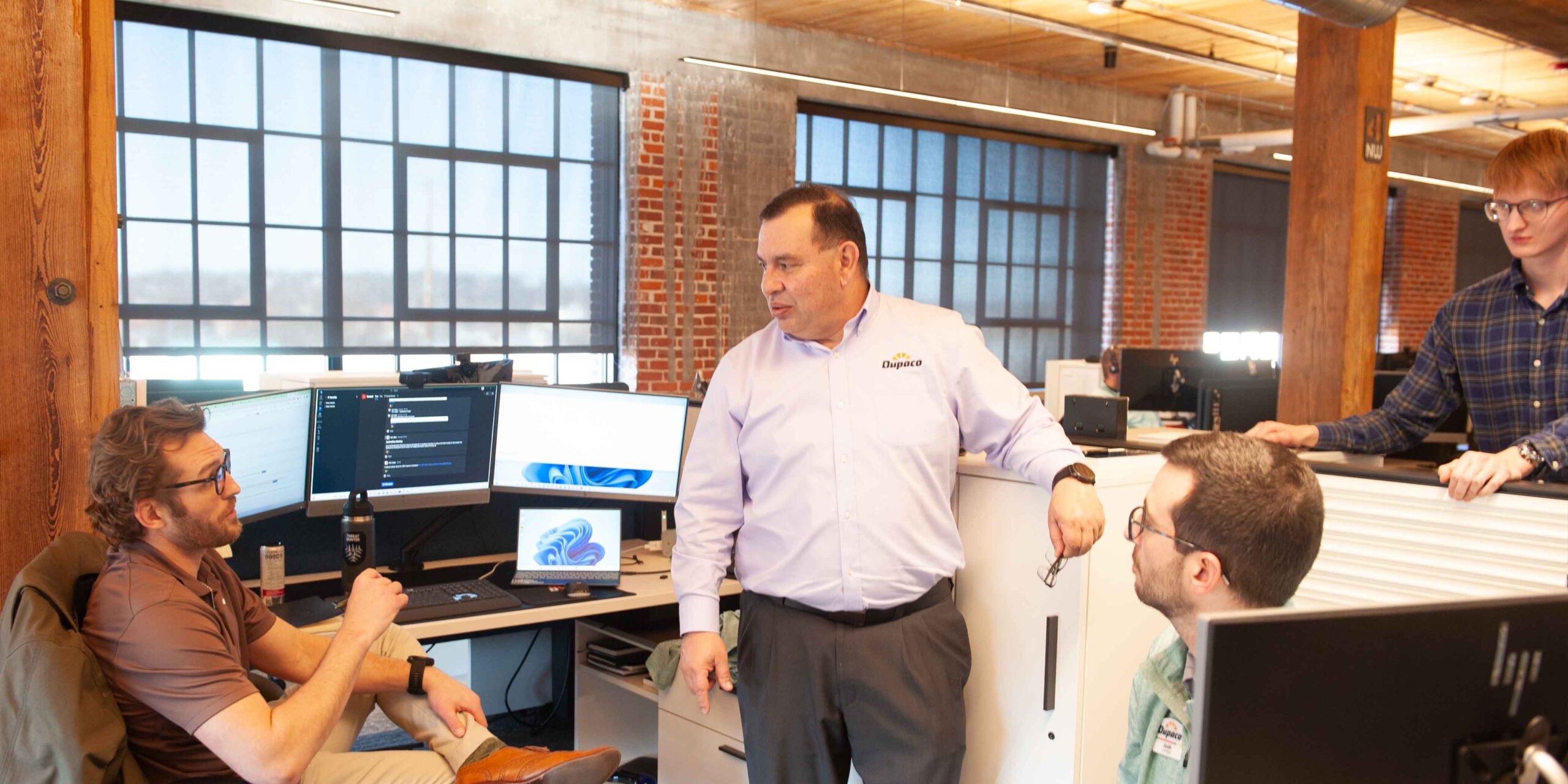 A group of people standing around a desk in an office.