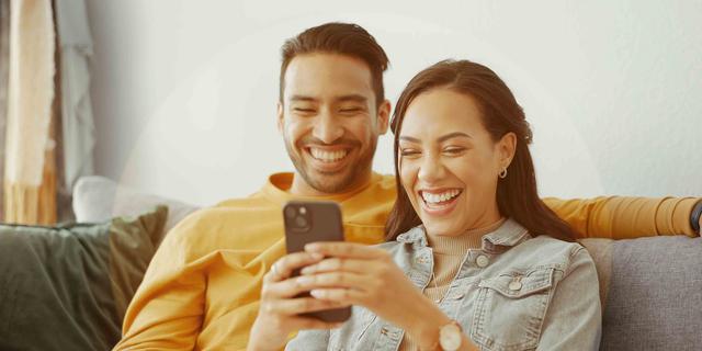 Young couple smiles as they look at their phone together